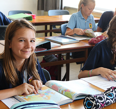 Eine Schülerin mit einem aufgeschlagenen Atlas im Klassenraum